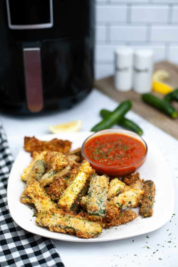Air Fryer Zucchini Fries with a side of marinara sauce on a white plate.