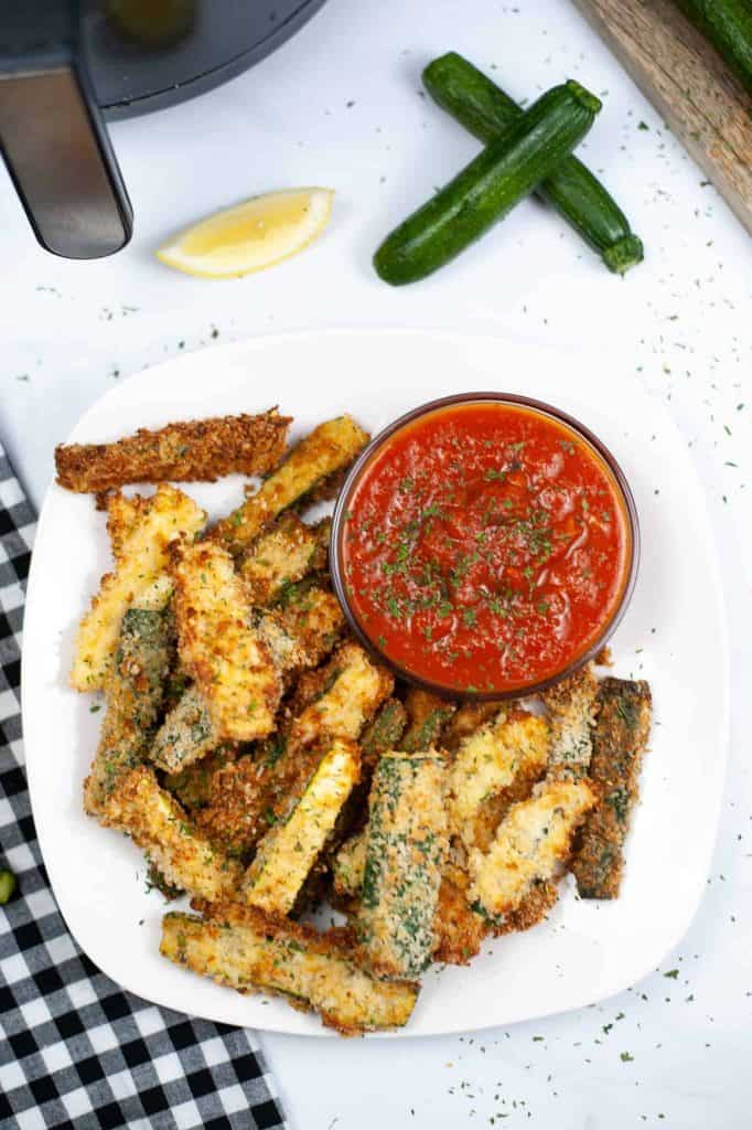 Overhead view of zucchini fries with marinara sauce.