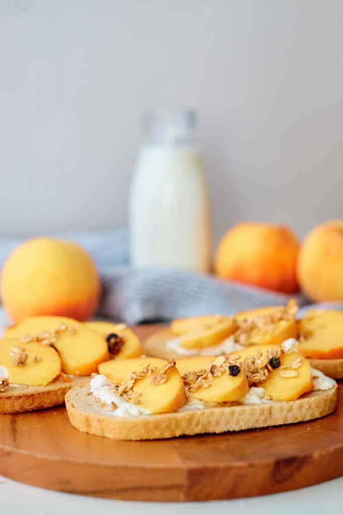 Peach toast on a wood cutting board with milk in the background.