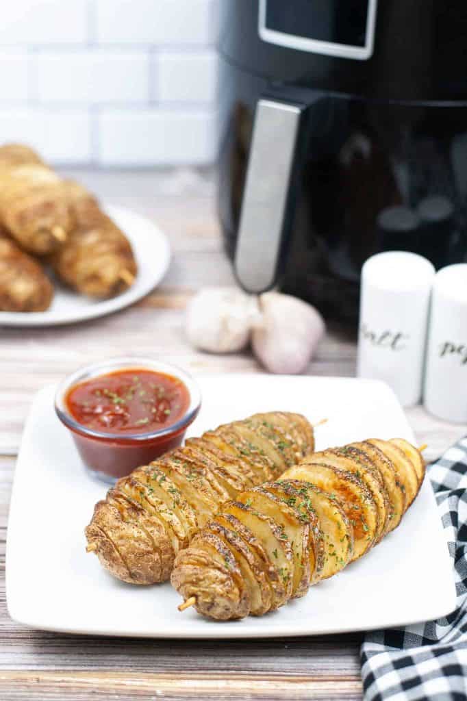 Tornado potatoes on a white plate with an air fryer behind it.