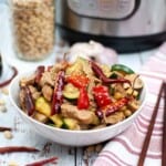 Asian chicken in a white bowl with chopsticks on the side.