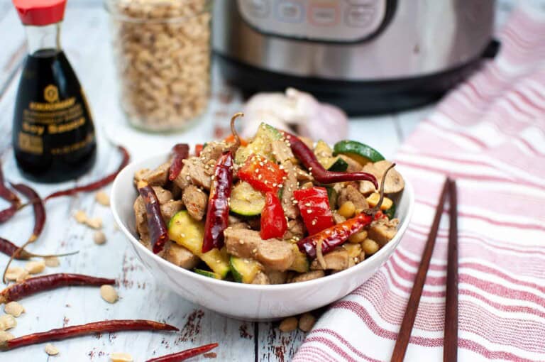 Asian chicken in a white bowl with chopsticks on the side.
