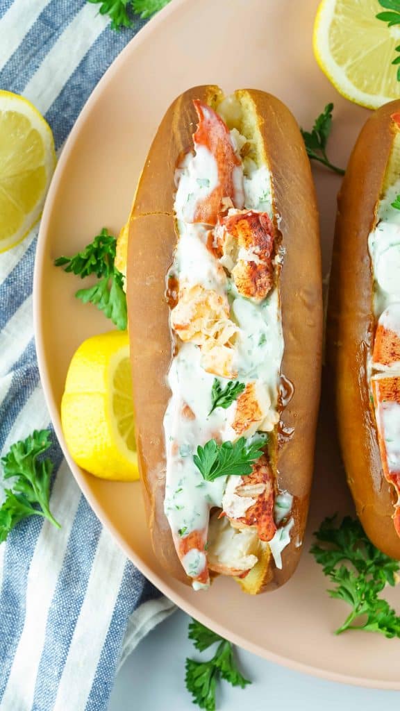 Overhead view of lobster roll on a plate with parsley and a lemon slice.