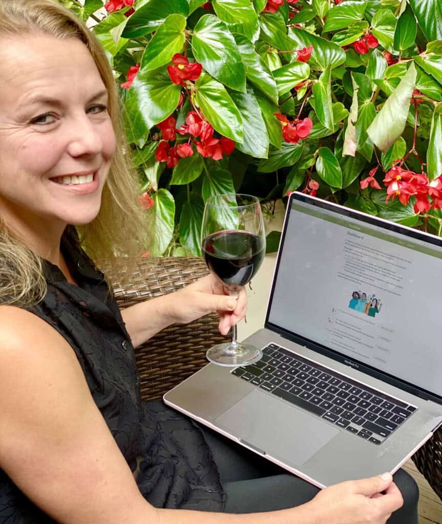 Attractive woman sitting with laptop holding a glass of red wine.