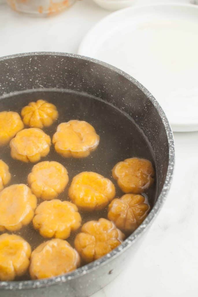 Boiled pumpkin gnocchi floating in a pot of water.