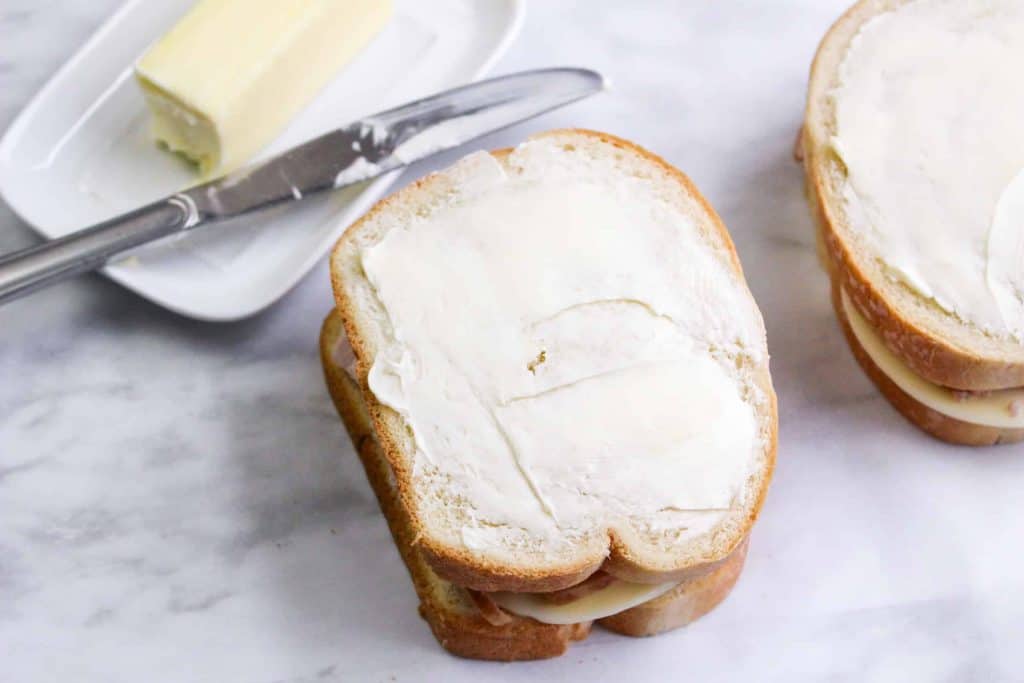 Buttering the bread before toasting it.