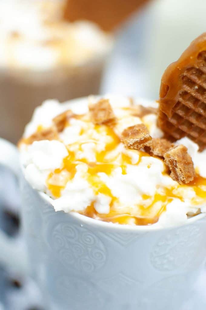 Closeup of Caramel Latte with whipped cream and a cookie.