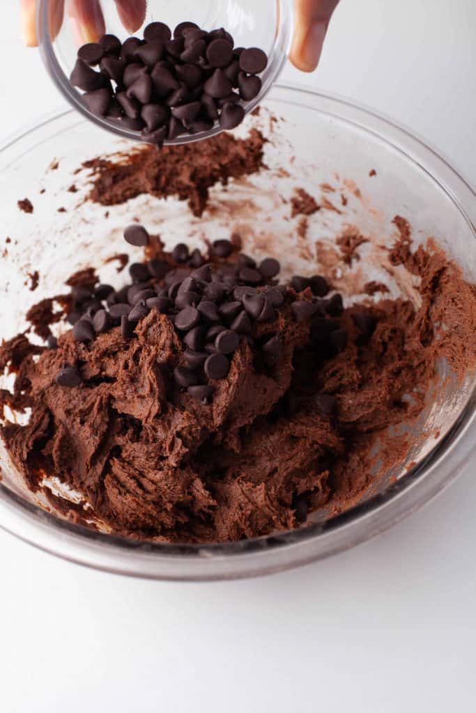 Adding chocolate chips to cookie dough.