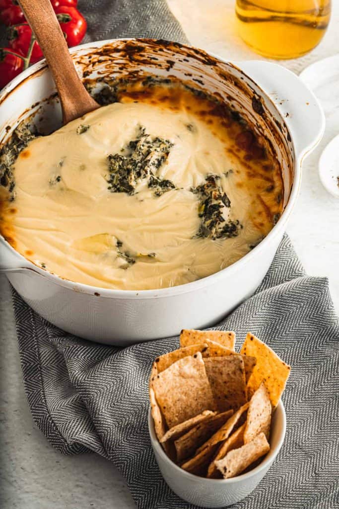 Baked artichoke spinach dip with cheese and tortilla strips.