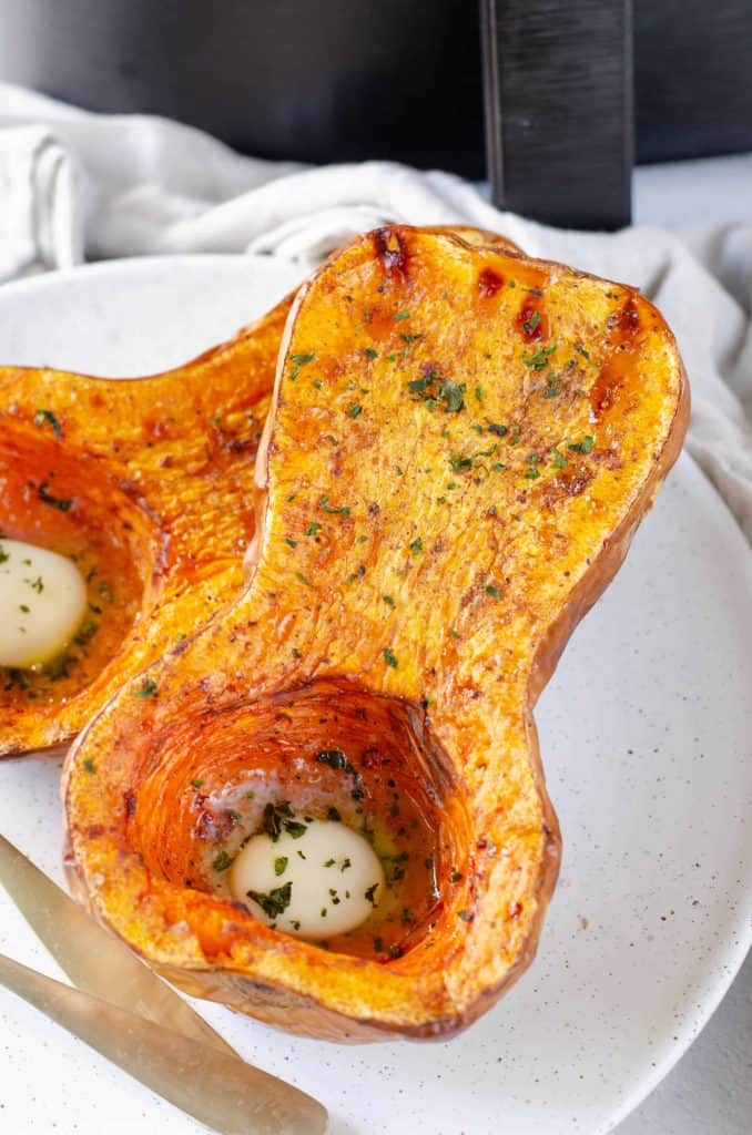 Overhead view of butternut squash with melted butter on a plate.