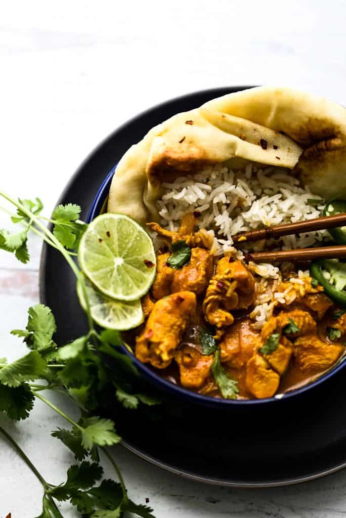 Instant Pot Butter Chicken over rice with naan and lime slices.