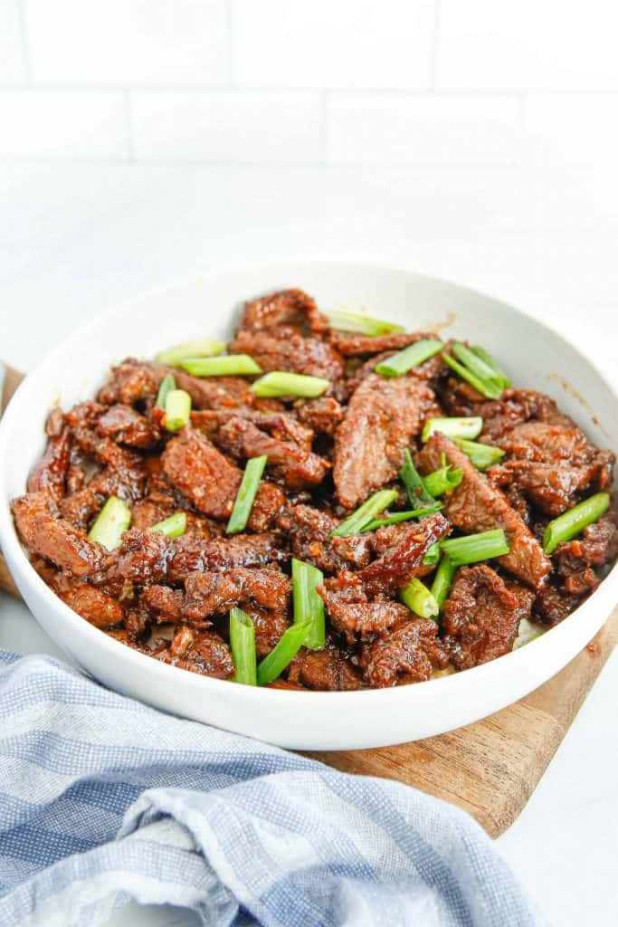 Mongolian beef in a white serving bowl.