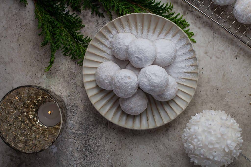 Overhead view of snowball cookies on a white plate.