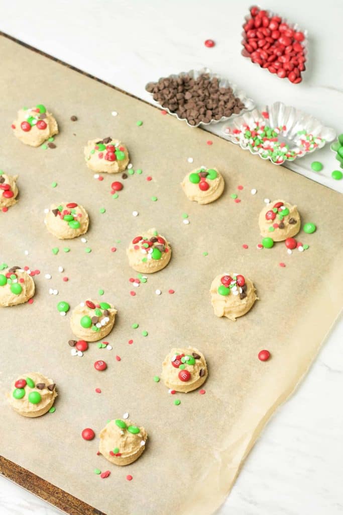 Peanut butter cookies with m&ms on a parchment lined baking sheet.
