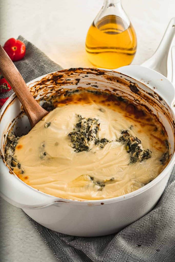 Spinach artichoke dip with a wood spoon in it.