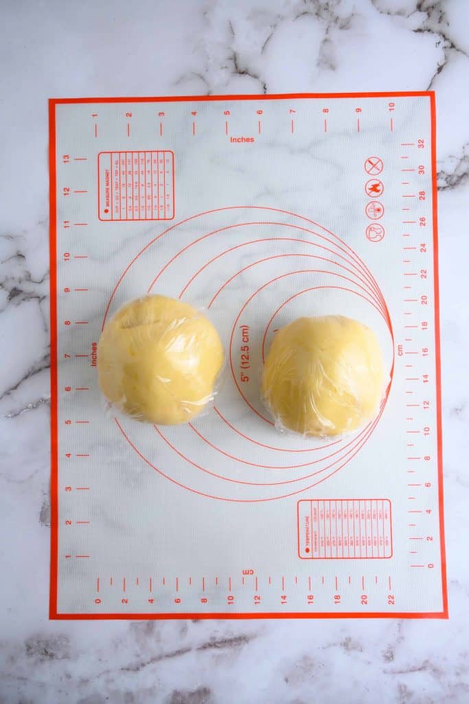 Two balls of sugar cookie dough wrapped in plastic.