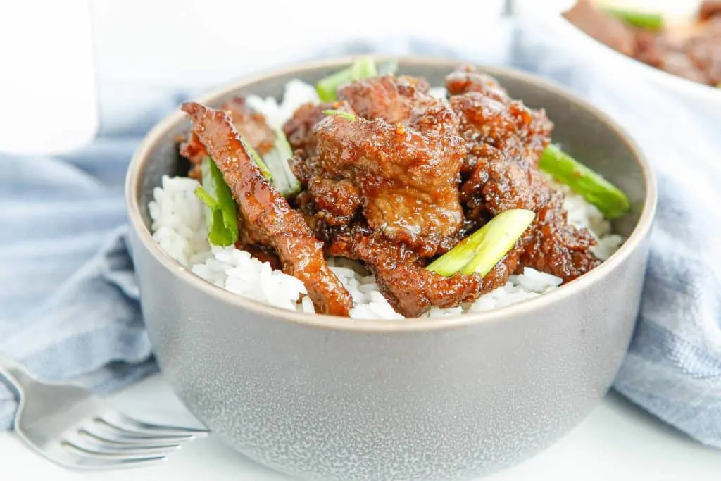 Bowl of Mongolian beef served over white rice.
