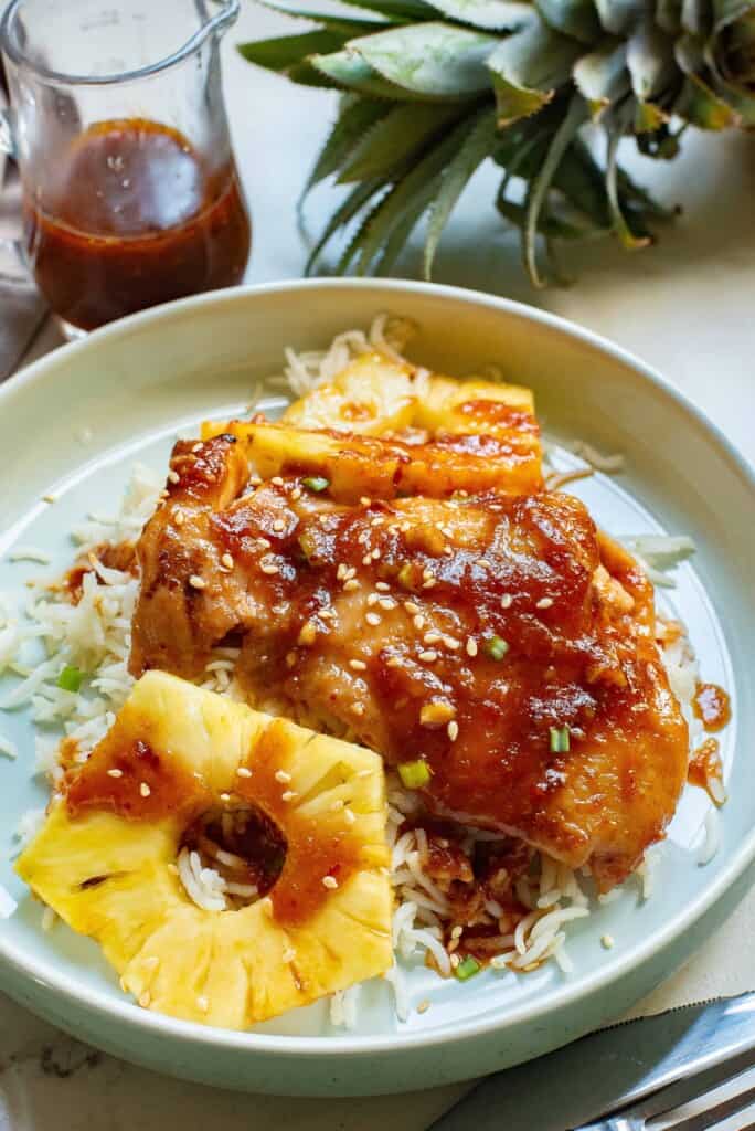 Air Fryer Hawaiian Chicken served over rice with pineapple slices on a white plate.