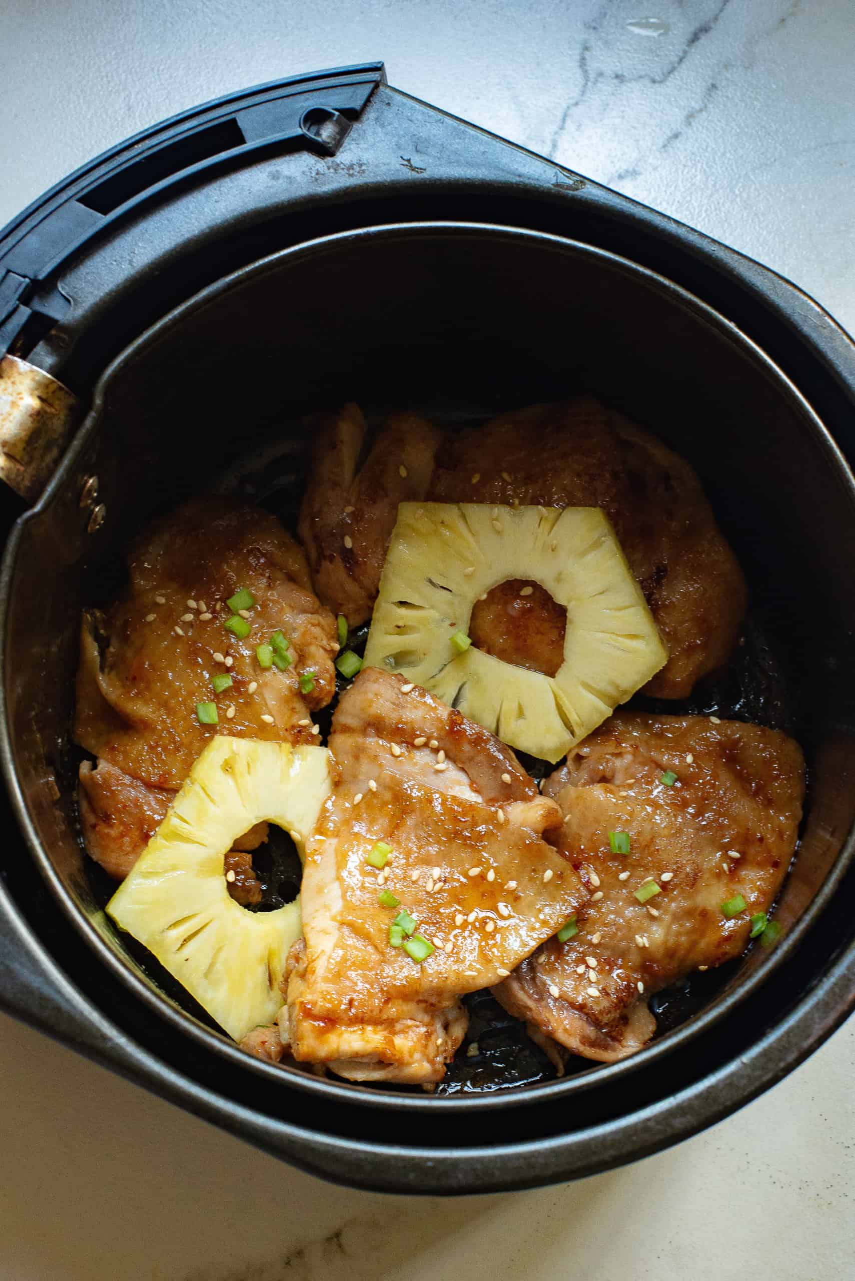 Overhead view of chicken with pineapple slices in air fire.