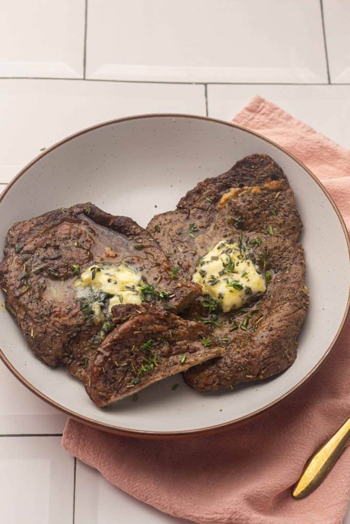 Air Fryer Steaks with Herbed Butter on a white plate.