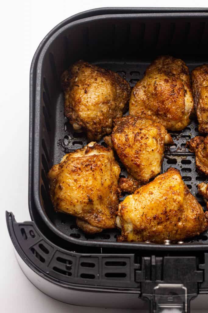 Overhead view of cooked chicken thighs in the air fryer