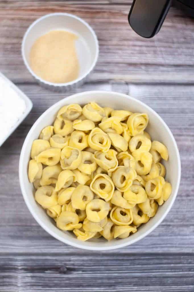 Overhead view of cooked tortellini in a white bowl.