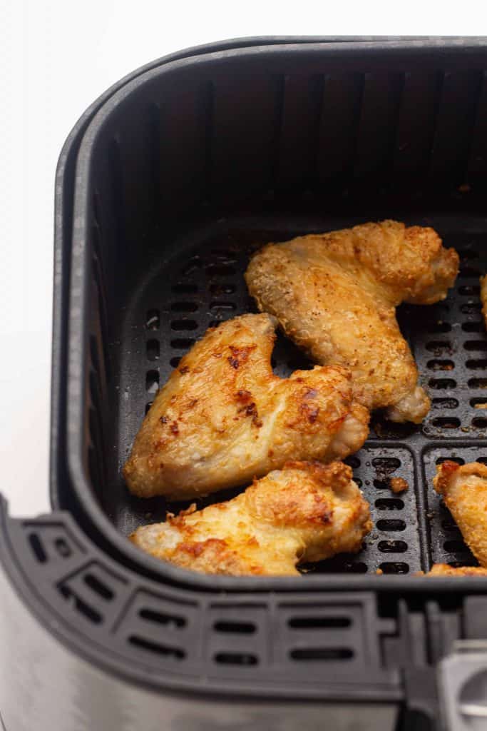 Crispy chicken wings in the air fryer basket.