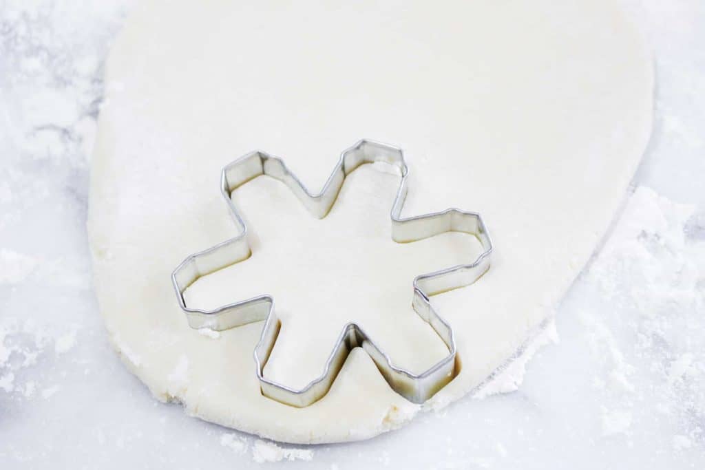 Cutting out snowflake sugar cookies
