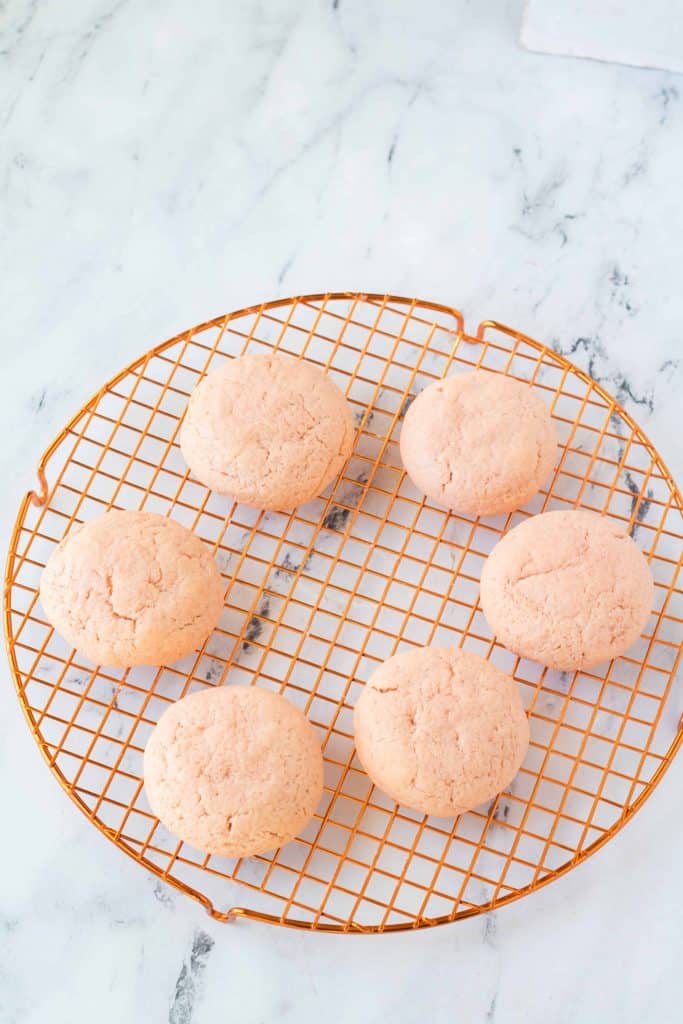 Baked strawberry cookies on a cooling rack.