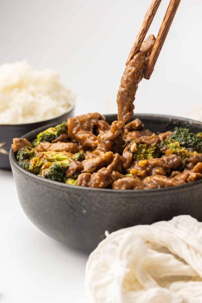 Beef and broccoli in a bowl with chopsticks.