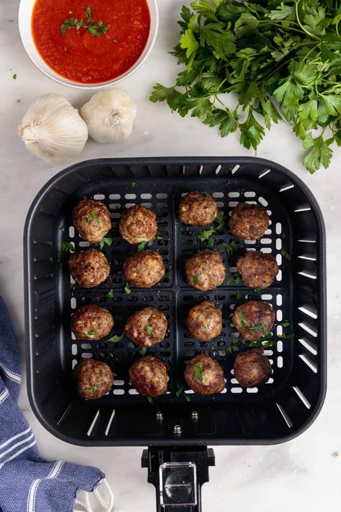 Meatballs in an air fryer basket.