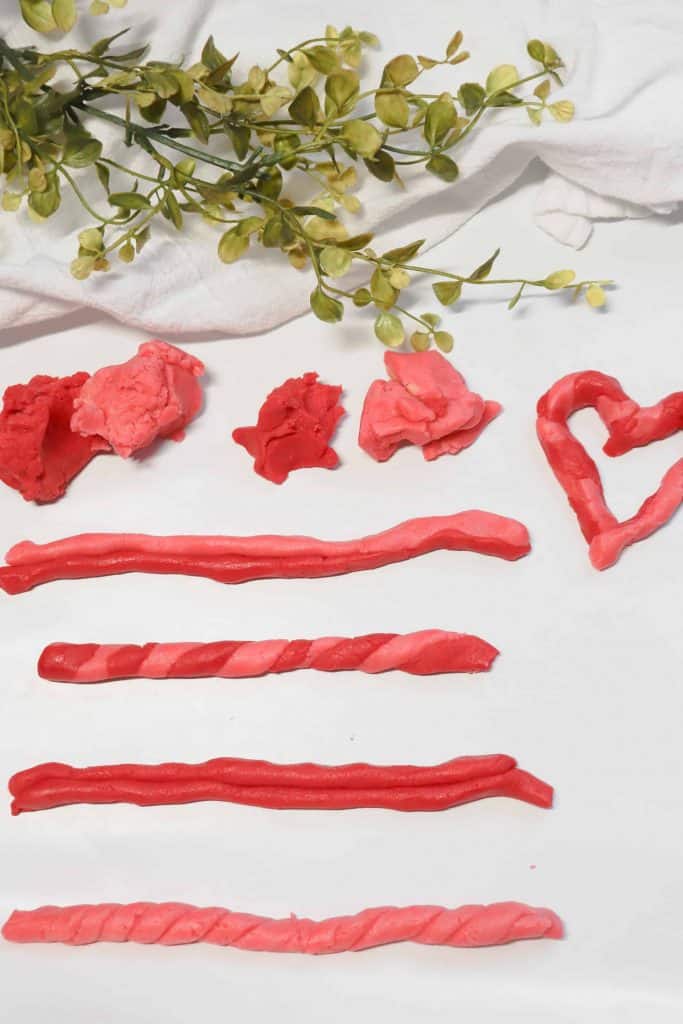 Creating heart shapes out of red and pink cookie dough.
