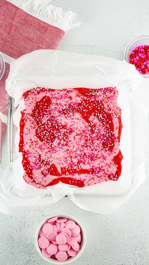 Strawberry fudge in baking pan lined with parchment paper.