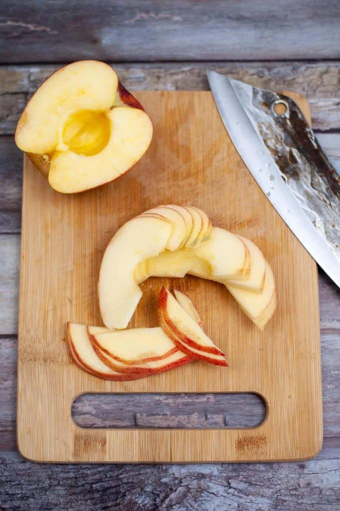 Thin slices of apple on a cutting board.
