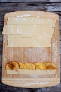 Apple slices lined up on edge of puff pastry.