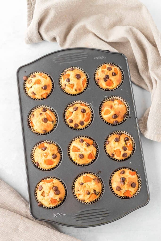 Orange chocolate chip muffins in a muffin tin.