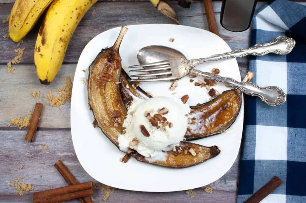 Overhead view of bananas with whipped cream on a white plate.