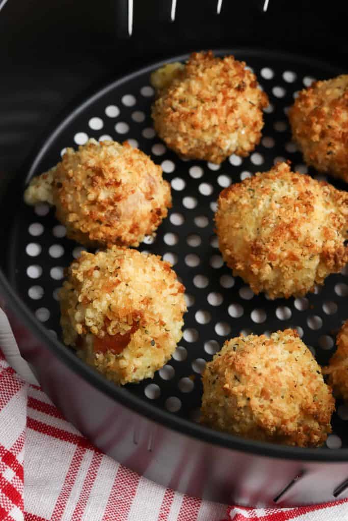 Pepperoni pizza bites in an air fryer basket.