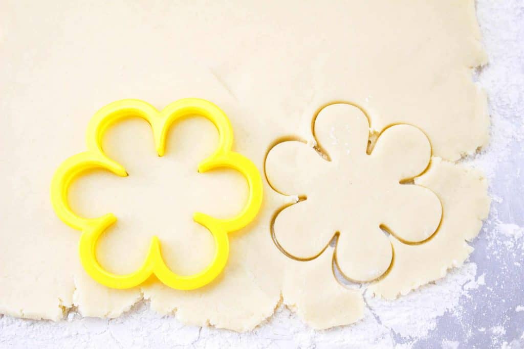 Cutting out flower sugar cookies.