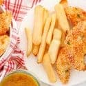 Overhead view of chicken tenders with French fries on a white plate.