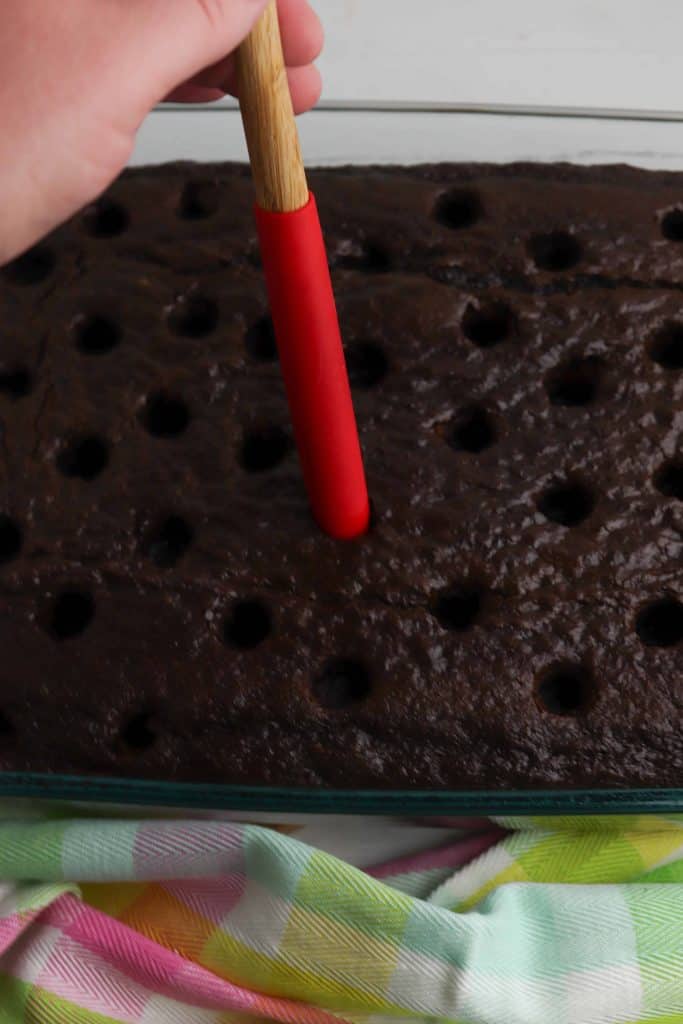 Poking holes in chocolate cake.