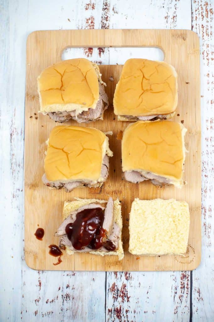 Preparing the pork sliders with barbecue sauce on Hawaiian rolls.