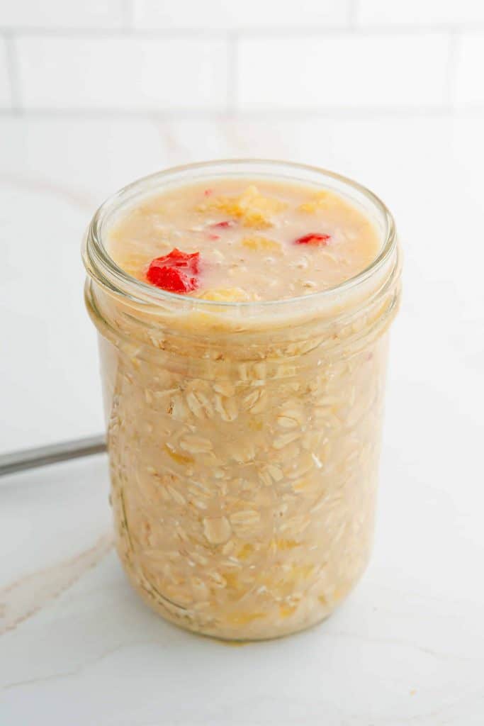 Overnight oats with pineapples and cherries in a Mason jar.