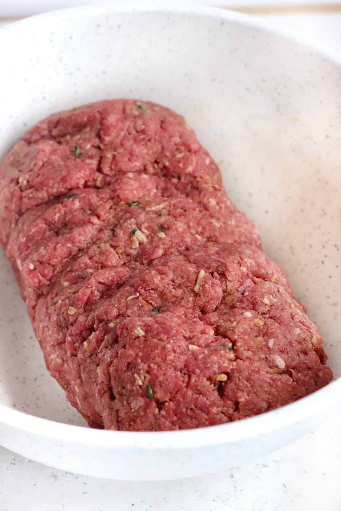 Formed loaf of meat in a white bowl.