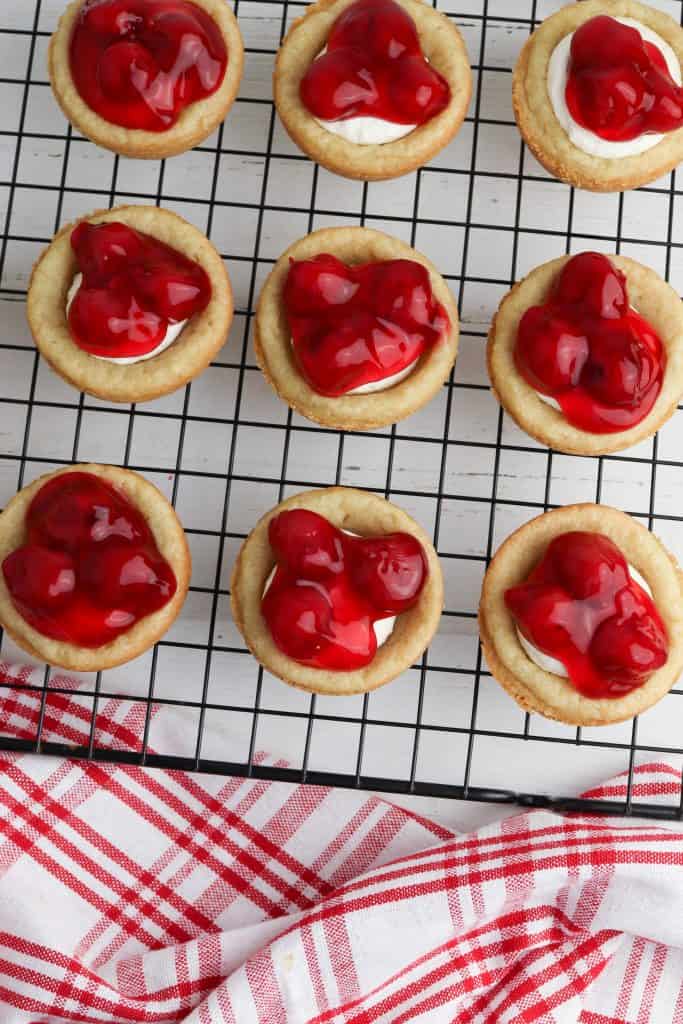 Cherry pie filling on top of cheesecake cookie cups.