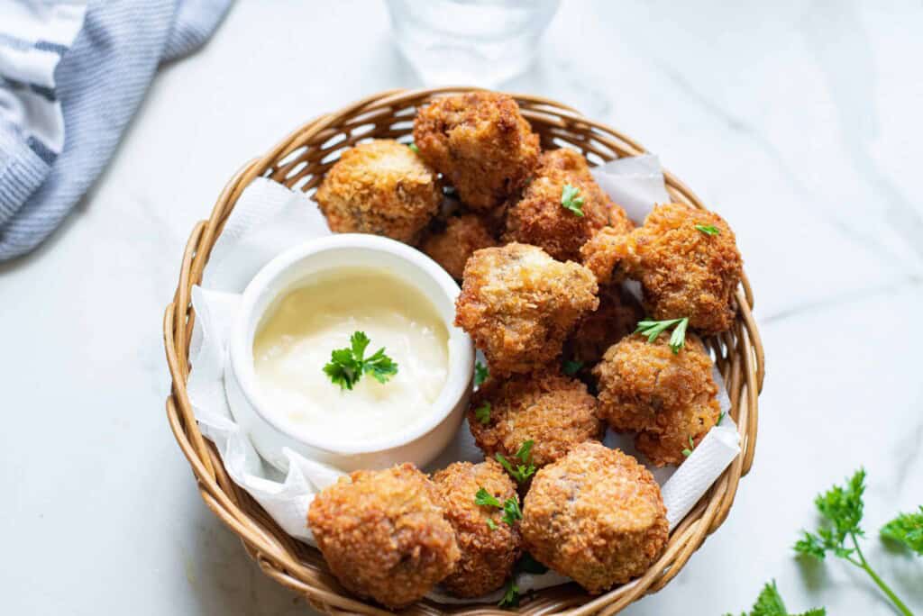 Fried mushrooms in a basket with sauce.