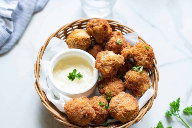 Fried mushrooms in a basket with sauce.