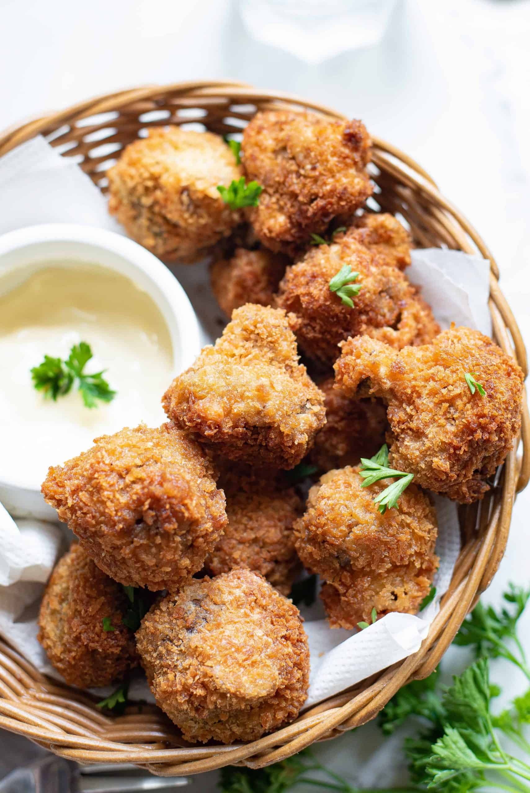 Overhead view of air fryer mushrooms in a basket with sauce.