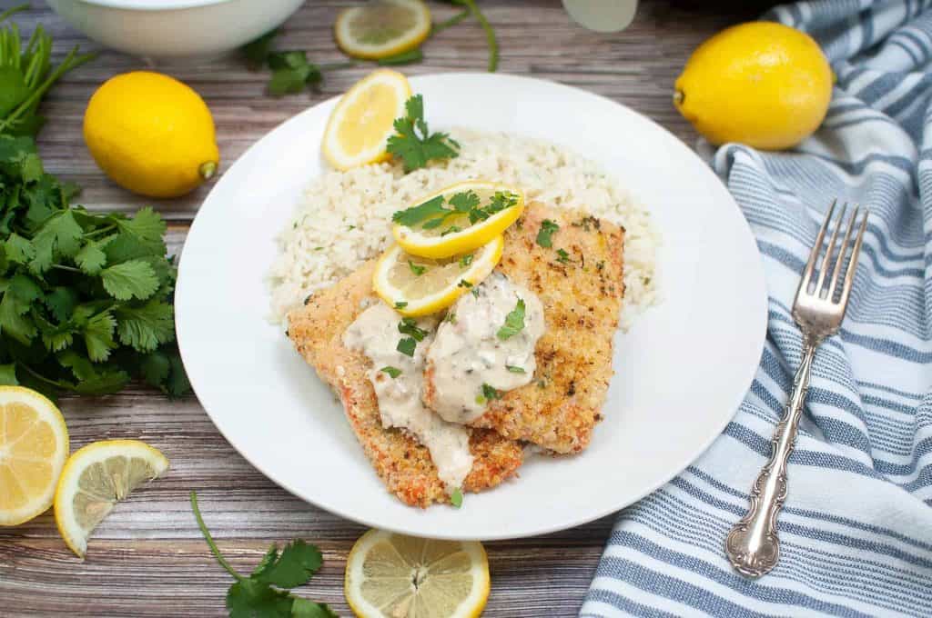 Parmesan crusted salmon with creamy wine sauce on a white plate.