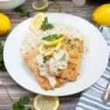 Parmesan crusted salmon with creamy wine sauce on a white plate.